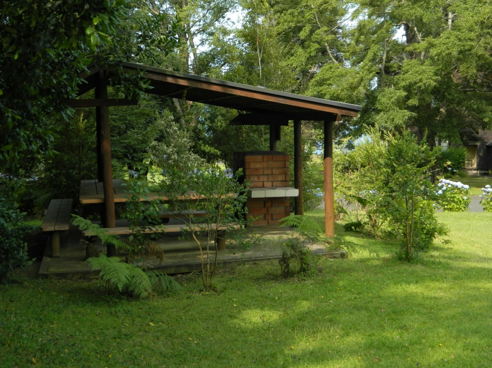 A wooden gazebo sits amongst lush greenery.
